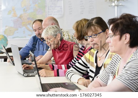 A group of elderly people looking at laptops.