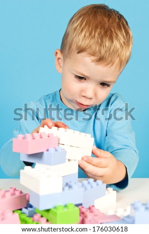 A boy playing with large pastel colored blocks.