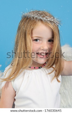 A little girl with angel wings and a halo smiling at the camera.