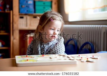 A young girl doing a wooden jigsaw puzzle.
