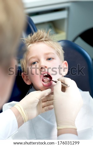 A boy having his mouth checked by a dentist with gloves on.