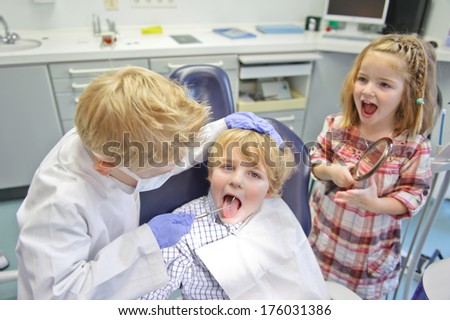 Three children, two boys and one girl, play in a dentist office.