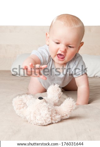 A baby on his knees enjoying his fluffy toy.