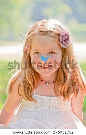 A little girl wearing floral hair clips outside.