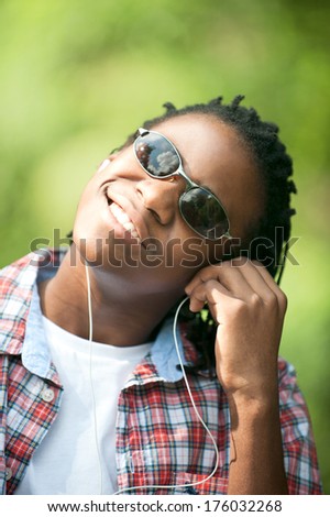 A man in sunglasses with earphones and his head tilted.