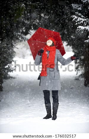 A woman stands outside in the falling snow.