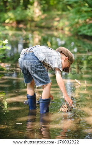 A boy wearing blue boots playing in water.