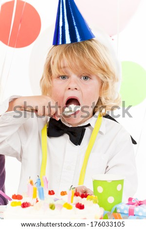 A boy in a party hat eating cake.