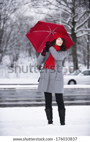 A woman holding a red umbrella and wearing a red scarf.