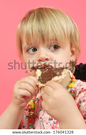 A little girl eating a chocolate covered piece of toast.