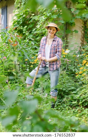 A lady in a plaid shirt is standing in a garden.