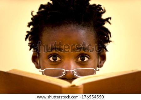 A person with glasses at the end of their nose reading a book.