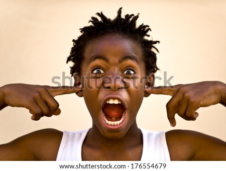 A boy yelling with his fingers in his ear.