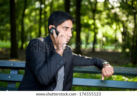 A guy talking on his cellphone sitting on a bench.
