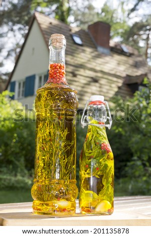 herbs in a bottle with olive oil in the garden with a house in the background