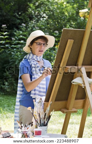 a woman painting a picture in the garden