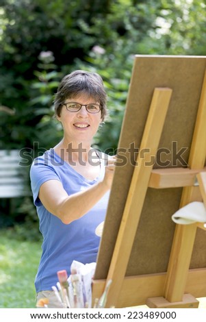 a woman painting a picture in the garden