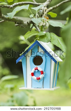 little bird\'s beach house hanging on a tree in the garden