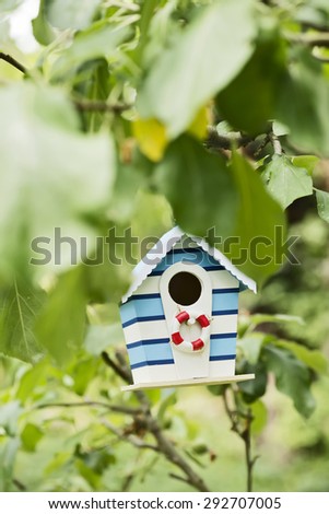 little bird\'s beach house hanging on a tree in the garden