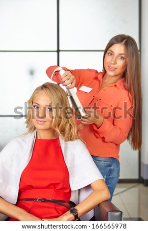 Hair salon. Women`s haircut. Use of straightener.