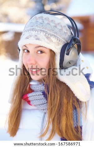 Outdoors on a winter day. Woman listening music.