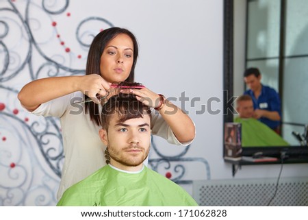 Hair salon. Hairdresser does haircut for man.