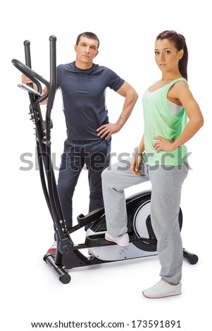 Young man and woman with elliptical cross trainer.