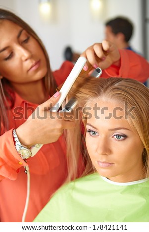 Hair salon. Woman haircut. Use of straightener.