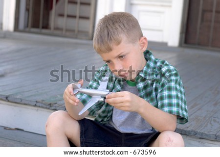Boy on porch dreaming with toy plane
