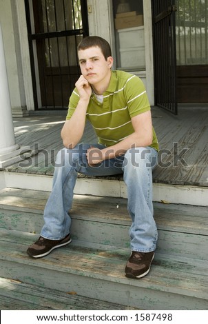 Young male sitting on an old wooden porch - looking bored and wanting something fun to do.