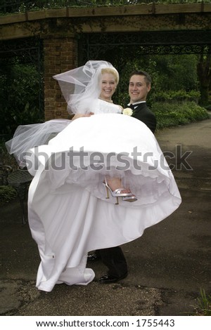 loving couple on their wedding day - groom is lifting the bride