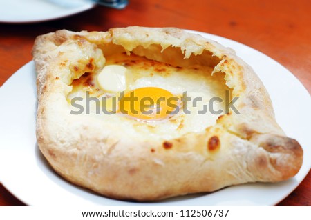 Ajarian or Adjaruli khachapuri, filled with cheese and topped with a raw egg and butter - traditional dish of georgian cuisine
