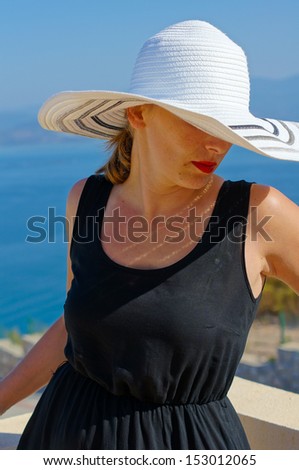 Beautiful woman in a straw hat on the villa\'s roof with view to Aegean sea