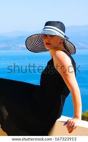 Beautiful woman in a straw hat on the villa\'s roof with view to Aegean sea