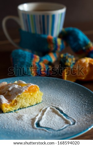Orange pie with sugar powder and tangire fruits on the wooden table