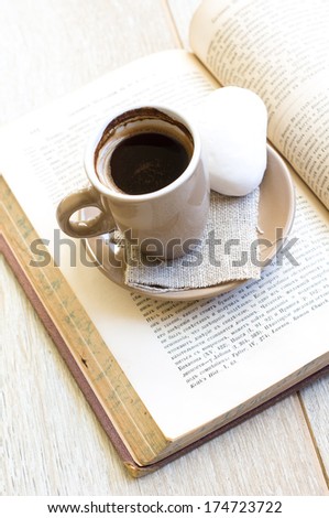 Cup of coffee, old book and notepad on the wooden table