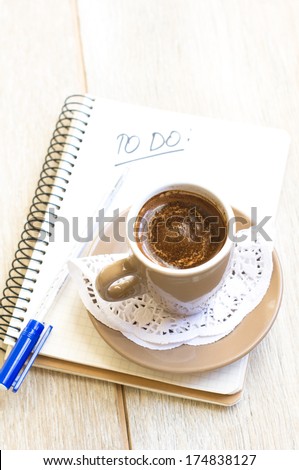 Cup of coffee, old book and notepad on the wooden table