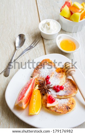 Healthy food, pakcakes with fresh fruits, honey and sour cream, green tea