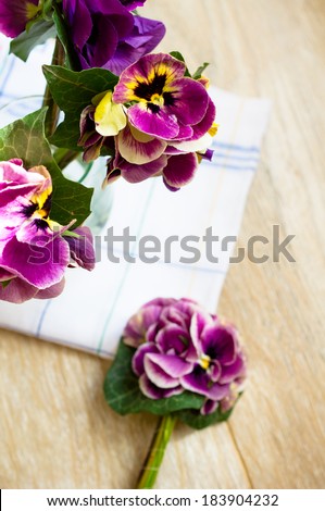 Viola flowers in a vase, old-styled clock and Good morning note on the table