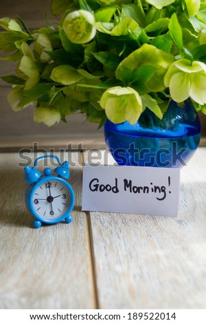 Old-styled clock Hellebore flowers and Good morning note on the table