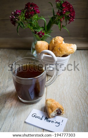 Croissant with chocolate, flowers and coffee with good morning note