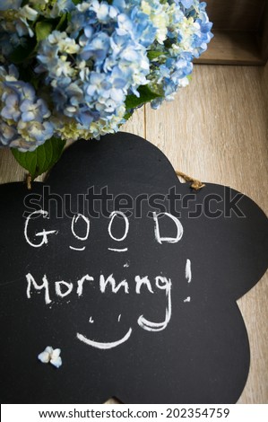 Blue pastel color hydrangea flowers and good morning note on wooden table
