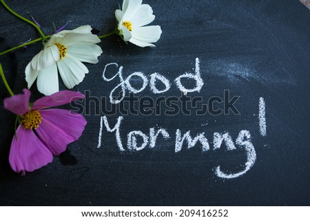 Vase with coreopsis flowers on the wooden table and good morning note