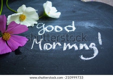 Vase with coreopsis flowers on the wooden table and good morning note