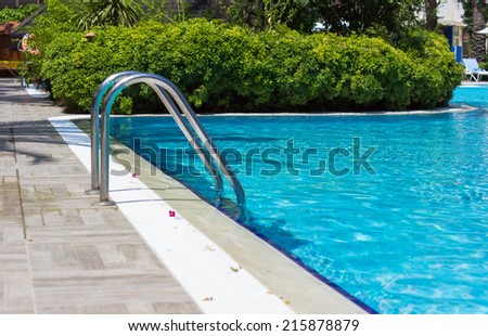 Outdoor pool in the tropical area with blue water and lader