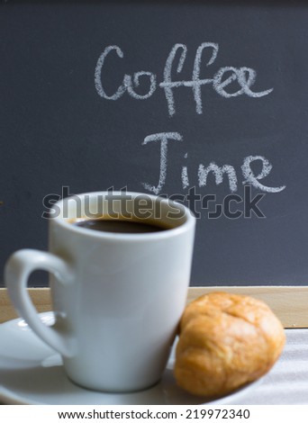 Cup of black coffee and croissants on the chalkboard with coffee time note