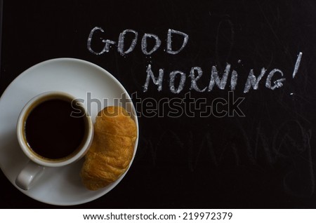 Cups of black coffee, croissants on the chalkboard with good morning note