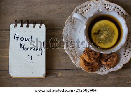 Cup of tea with lemon and cookies on the table with Good morning note