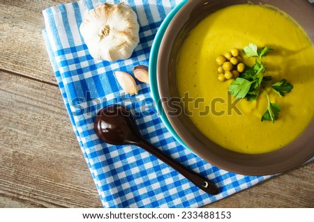 Fresh green pea soup with pea seeds and pea pods around. Selective Focus