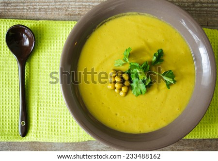Fresh green pea soup with pea seeds and pea pods around. Selective Focus